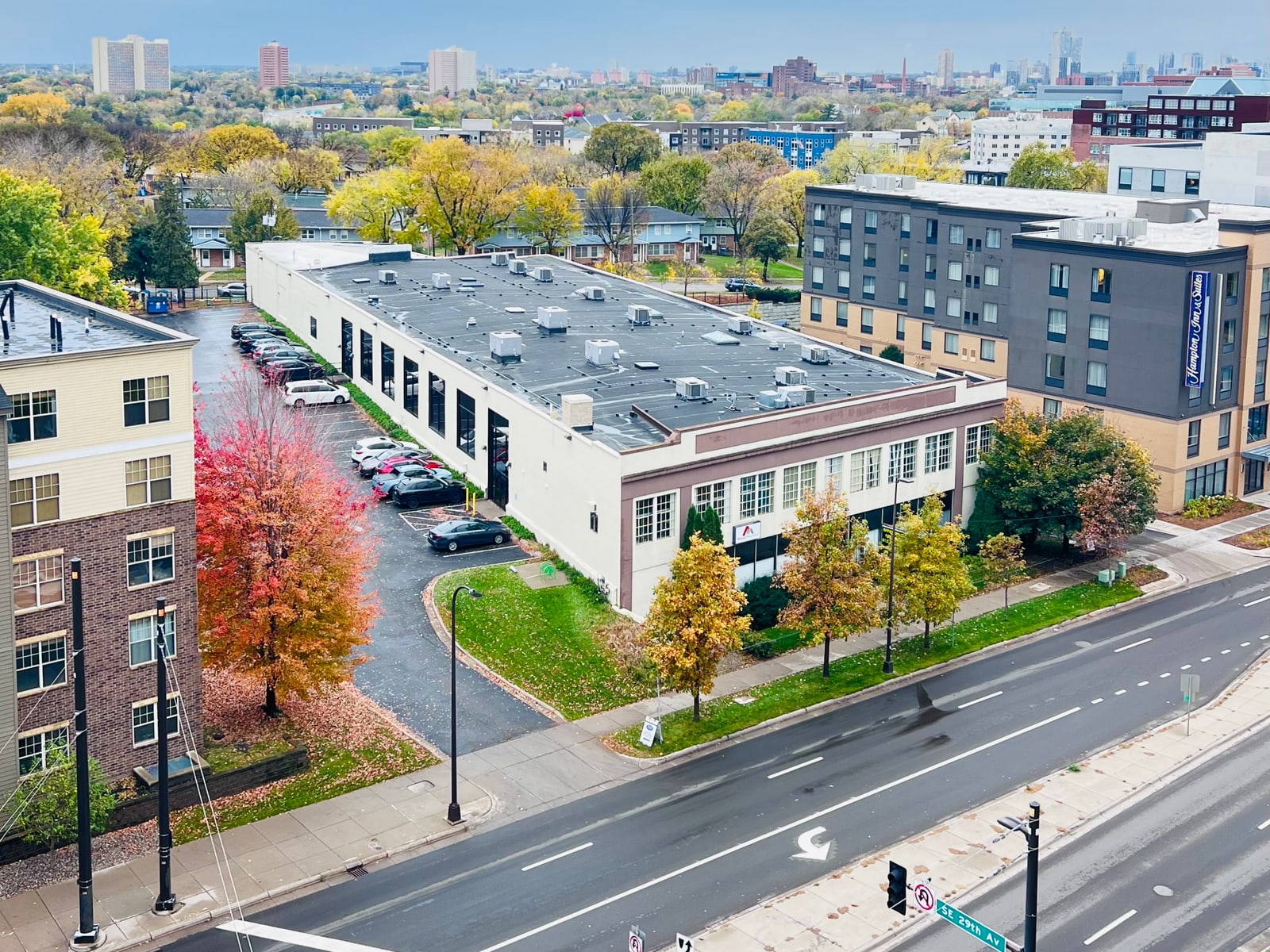 2828 University Avenue SE from above, with the parking lot, University Avenue, and the Minneapolis skyline behind